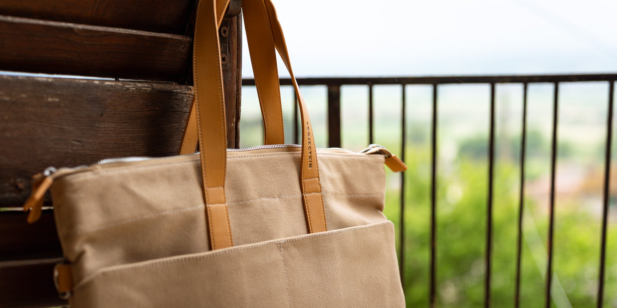Projectkin bag with brown straps on a wooden surface with a blurred outdoor background